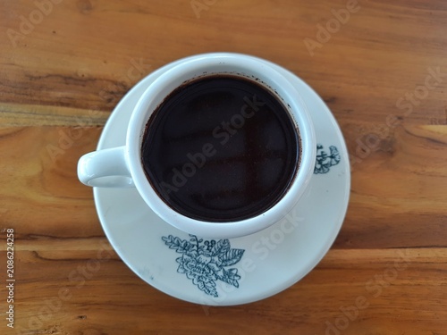 Cup of Black Coffee on Saucer with Floral Pattern on Wooden Table. Business Background
