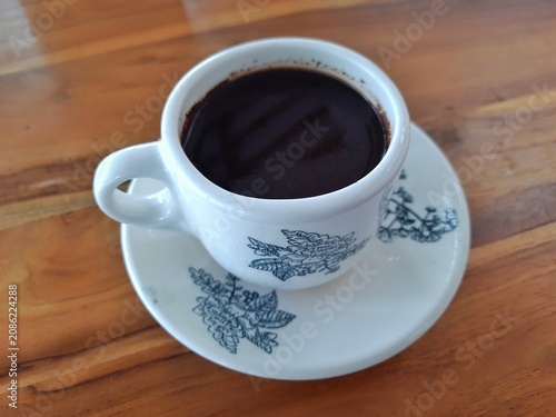 Cup of Black Coffee on Saucer with Floral Pattern on Wooden Table. Business Background