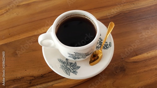 Cup of Black Coffee on Saucer with Floral Pattern on Wooden Table. Business Background