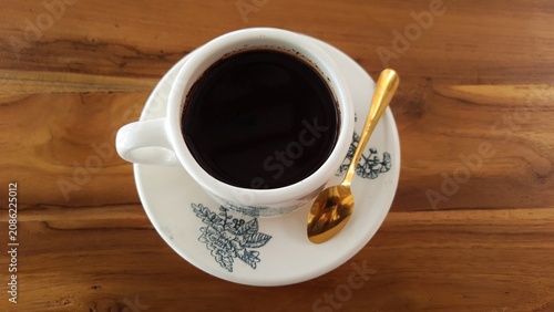 Cup of Black Coffee on Saucer with Floral Pattern on Wooden Table. Business Background