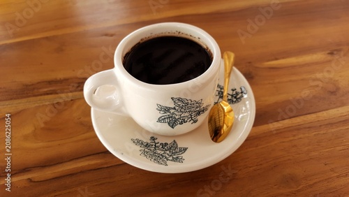 Cup of Black Coffee on Saucer with Floral Pattern on Wooden Table. Business Background
