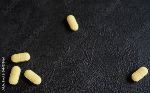 Canvastavla Several oval, yellow tablets with a score line down the middle are placed on a textured black surface