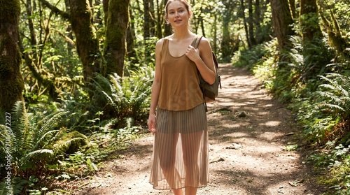 Attractive female hiker walking down nature trail inside lush green dense mossy forest