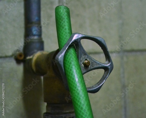 Bilde på lerret Industrial water valve locked with a green rubber hose, concept of resource limitation or water saving