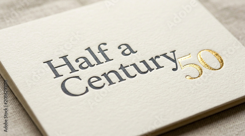 Elegant 50th anniversary card with gold foil text, half a century celebration invitation on textured paper, luxury golden jubilee stationery