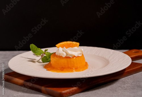 Orange Jelly Dessert with Whipped Cream and Fresh Orange Slice on White Plate,perfect for bakery, café, restaurant, and sweet treat concepts.