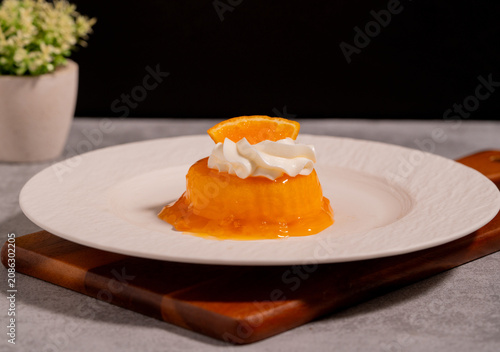 Orange Jelly Dessert with Whipped Cream and Fresh Orange Slice on White Plate,perfect for bakery, café, restaurant, and sweet treat concepts.
