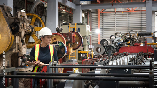 Fotografie Female engineer in hard hat and high visibility vest inspects metal coil product