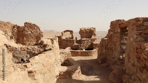 Sun-drencher ancient ruins of traditional fortified structures of Ksar Beni Barka with remains of mud brick rooms used for dwelling and granaries, Tataouine, Tunisia