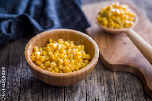 Foto Fresh Sweet Corn Kernels in Wooden Bowl on Rustic Table With Blue Napkin Backgro
