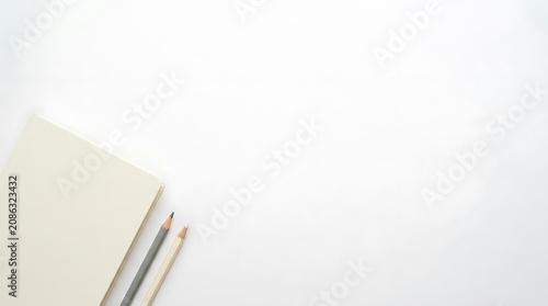 Open notebook and pencils on white surface with copy space
