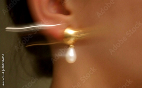 A photo of a woman wearing elegant pearl earrings wobbling her ears