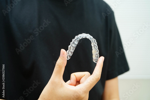 Fotografie Man holding invisible aligner orthodontic retainer for dental teeth straightening