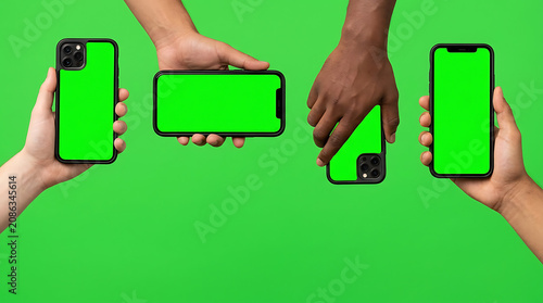 Four hands holding smartphones with green screen displays against a vibrant background