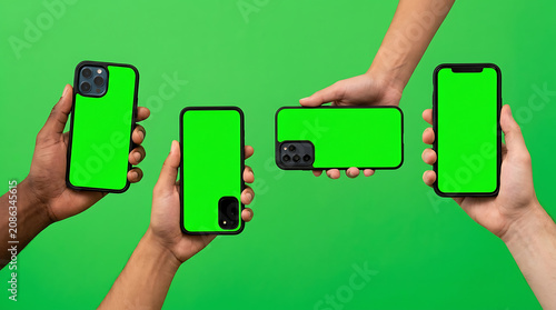 Four hands holding smartphones with green screen displays against a solid green background