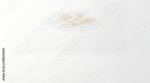 Small brown specks scattered on a clean white background in a minimalist studio shot