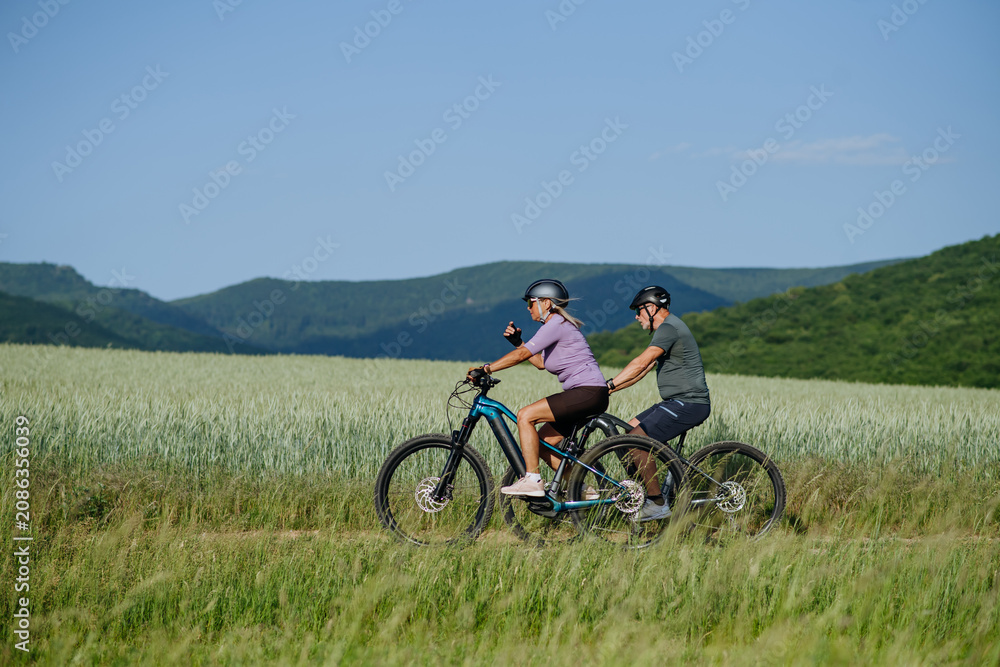 Fototapeta premium Active senior couple exploring nature on electric bicycles