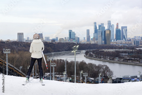Skier overlooking modern city skyline from snowy mountain slope, winter urban lifestyle and recreation. Work-Life Balance