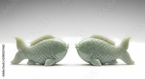 Two Serene Jade Fish Facing Each Other on White Background