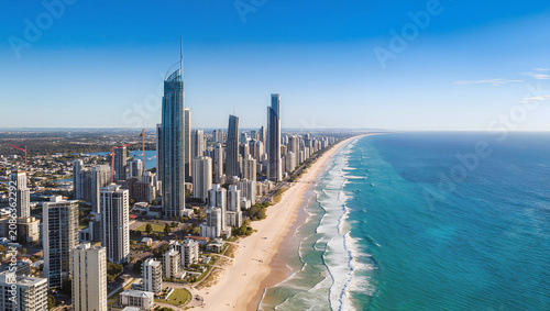Aerial view of a modern coastal city skyline with a long sandy beach and ocean waves