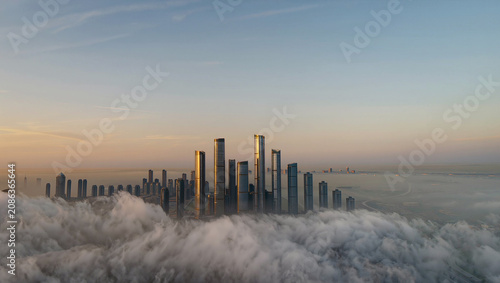 City skyline emerging from clouds at sunrise, modern skyscrapers, urban landscape