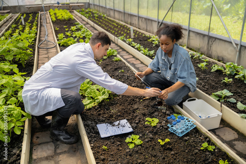 Practical agricultural studies of adolescent students, with scientists providing guidance, demonstrating hypotheses on soil sampling and data recording in greenhouse. Hands-on training in high school
