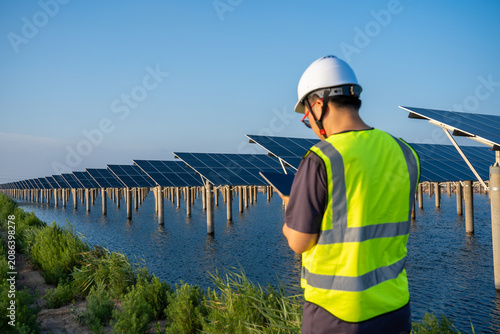 Engineer inspecting floating solar power plant with tablet