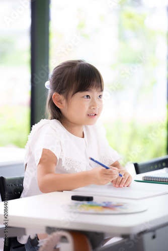 新緑の教室で黒板を見る勉強に集中して取り組む幼稚園・小学生位の女の子・塾や学校、受験や勉強、学習の勉強がわかった！ポジティブイメージ　縦
