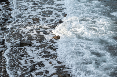 Abstract close-up of ocean waves foaming over rocks on the shoreline