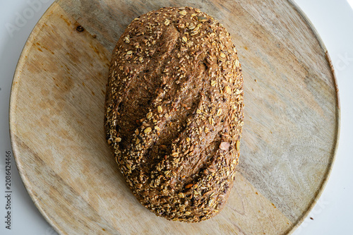 Fotografía Top down view of a wholesome multigrain seeded bread loaf on a round wooden board, an artisan loaf with a dark crust and plenty of grains and seeds