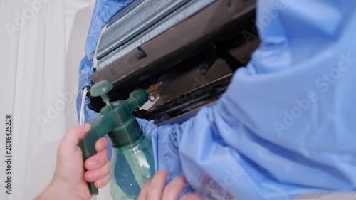 Professional hvac technician spraying a cleaning solution on the evaporator coil of a split air conditioner