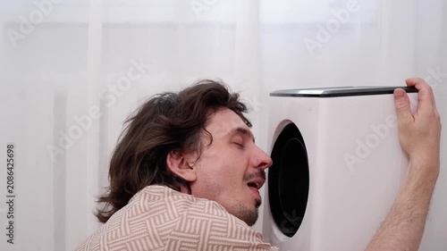 Young man cooling his face with an air cooler fan during extreme heat, enjoying the fresh air