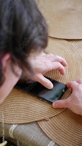 Male hands carefully applying a new screen protector film to a mobile phone on a wicker placemat