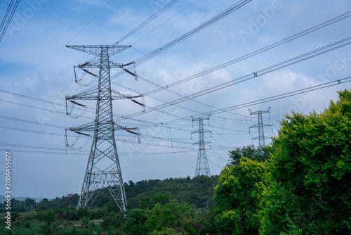 High Voltage Power Transmission Towers Over Green Landscape