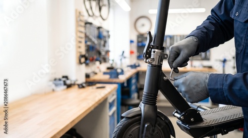 Mechanic adjusting electric scooter stem with tool in service shop