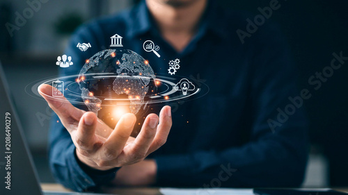 Businessman holding glowing digital hologram globe with global network and business icons