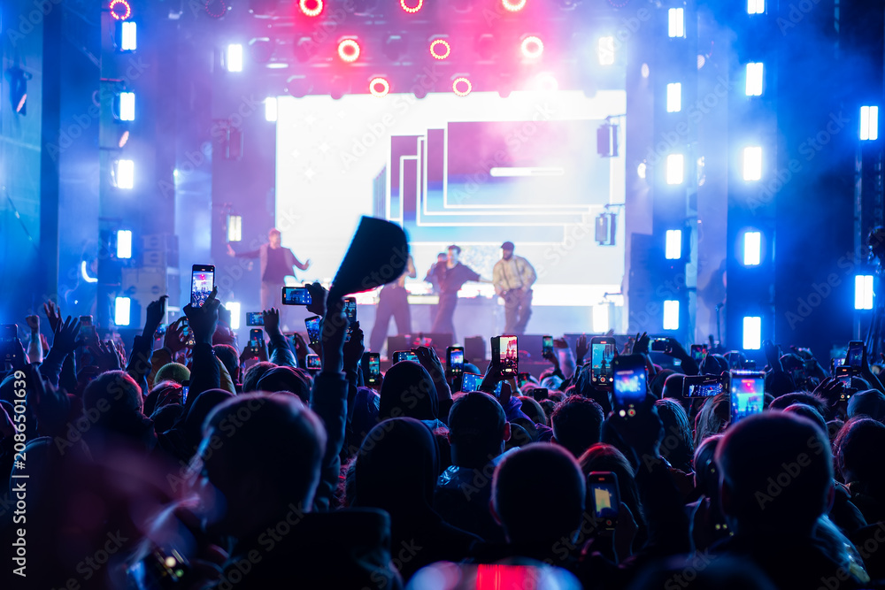Fototapeta premium street open air. big concert, a crowd of people welcomes their favorite musicians and takes pictures on their smartphone.