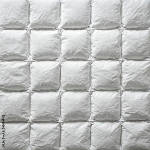 Close-up of a white quilted duvet or comforter with a grid pattern.