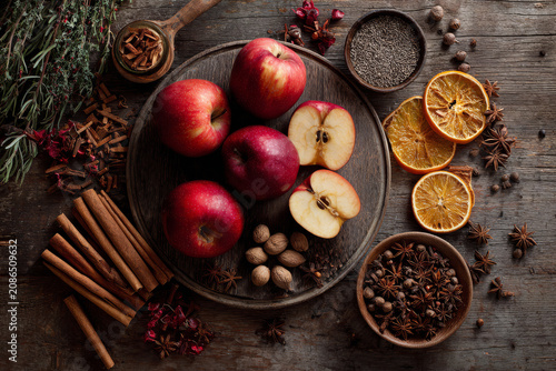 A rustic arrangement of fresh red apples and aromatic spices on a wooden table, perfect for autumn or holiday themes.