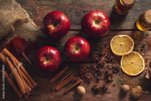 Autumn harvest ingredients for mulled cider or spiced apple pie, including fresh apples, cinnamon sticks, star anise, and dried lemon slices.