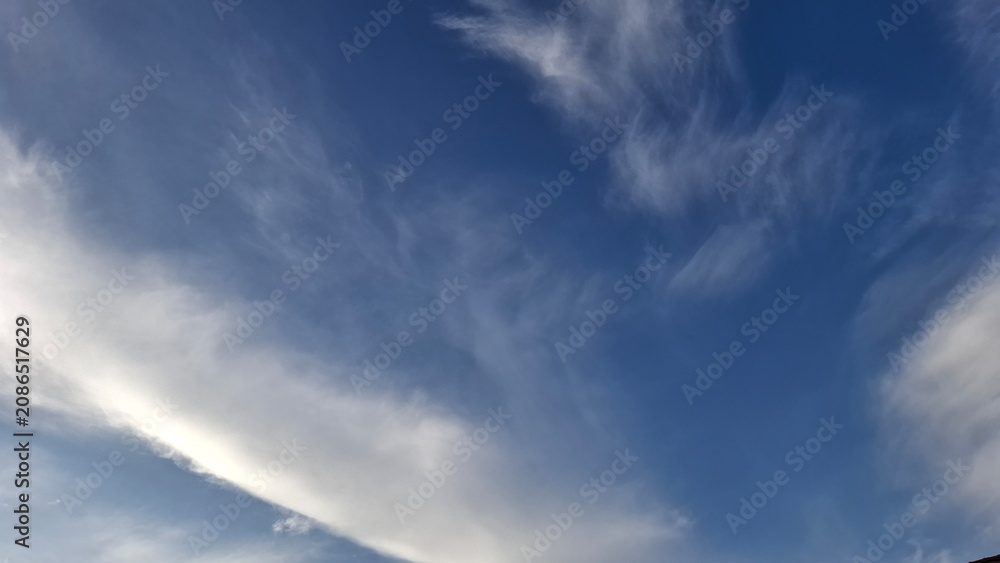 Obraz premium Wispy clouds spreading over quiet blue sky