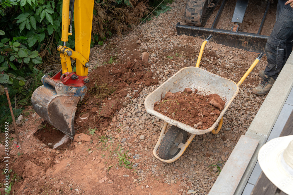 Fototapeta premium excavator bucket digging soil and rocks on construction site side view active yellow red natural light clean background copy space editorial educational visual story design resource web.