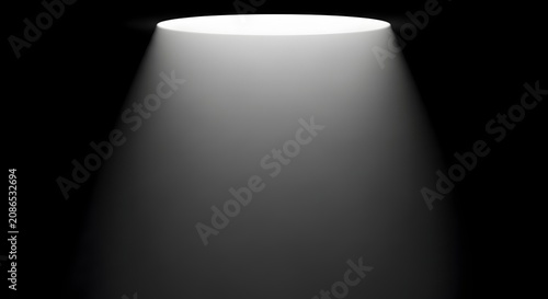 Dramatic white spotlight illumination effect shining on empty black background stage.