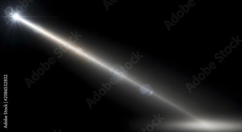 Bright spotlight beam with lens flare effects shining on dark surface