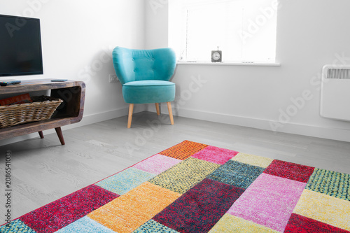 Interior view of a newly renovated apartment located in an old mill within the UK. Showing its modern design, white painted walls and colourful rug and fabric chair.