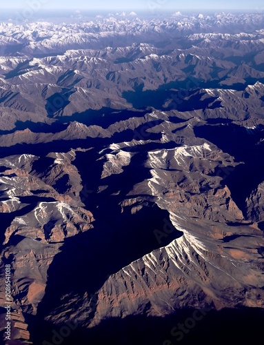 Aerial view of rugged alpine peaks under dramatic light and shadow