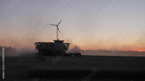 Handheld Silhouette of Combine Harvester and Wind Turbine at Dusk
