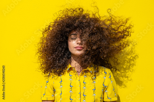 Curly hair blowing in the wind against a yellow background