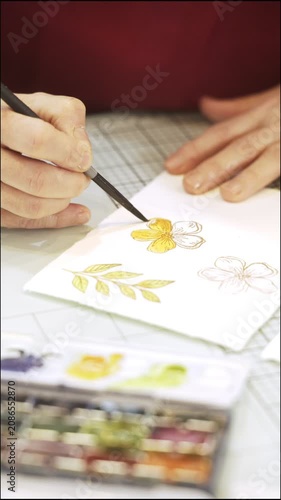 Woman's hands painting a watercolor flower for scrapbooking