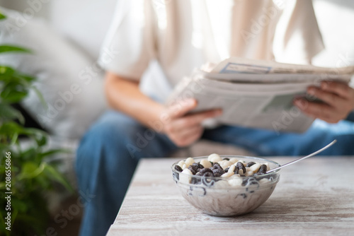 фотографія Person relaxing at home, having a leisurely breakfast with cereal and milk, whil